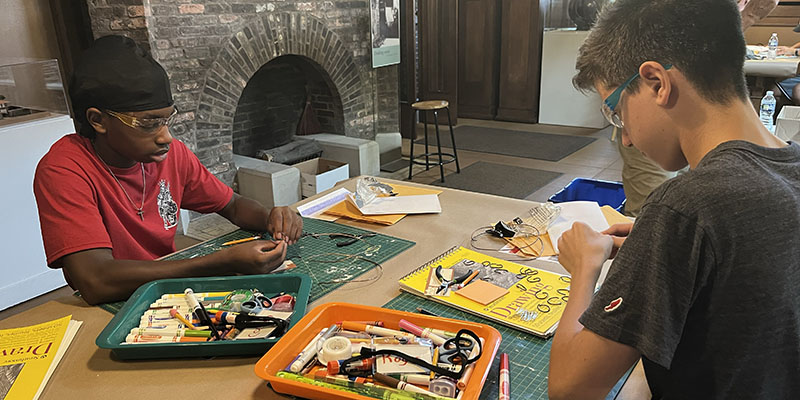 Two campers wear safety goggles and cut copper wires as preservationist Doug Freerksen leads a workshop.