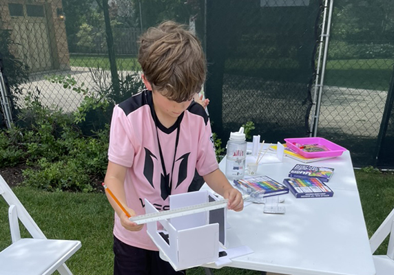 A camper takes measurements of his model mid-construction.