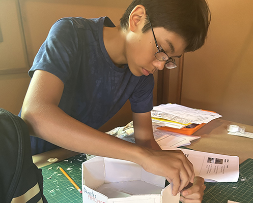 A camper focuses on putting together the walls of his model.