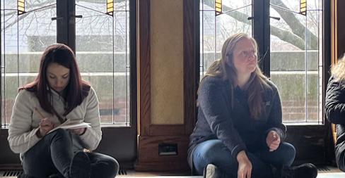 Educators sitting in front of Robie House windows