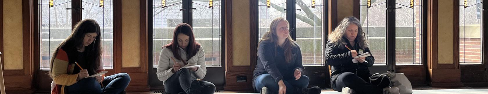 Educators sitting in front of Robie House windows